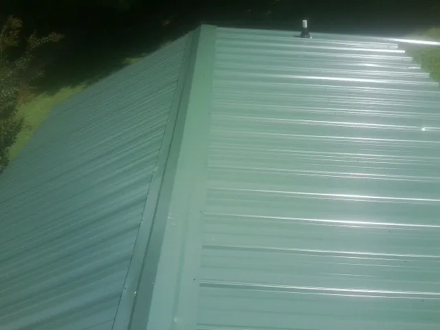 New green metal panels meeting at the ridge of a roof — Flat Roof Repair work by our crew in Aquasco