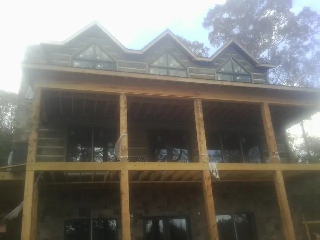 Dormers and porch framing on a large log home under construction — Roof Coating work by our crew in Aquasco