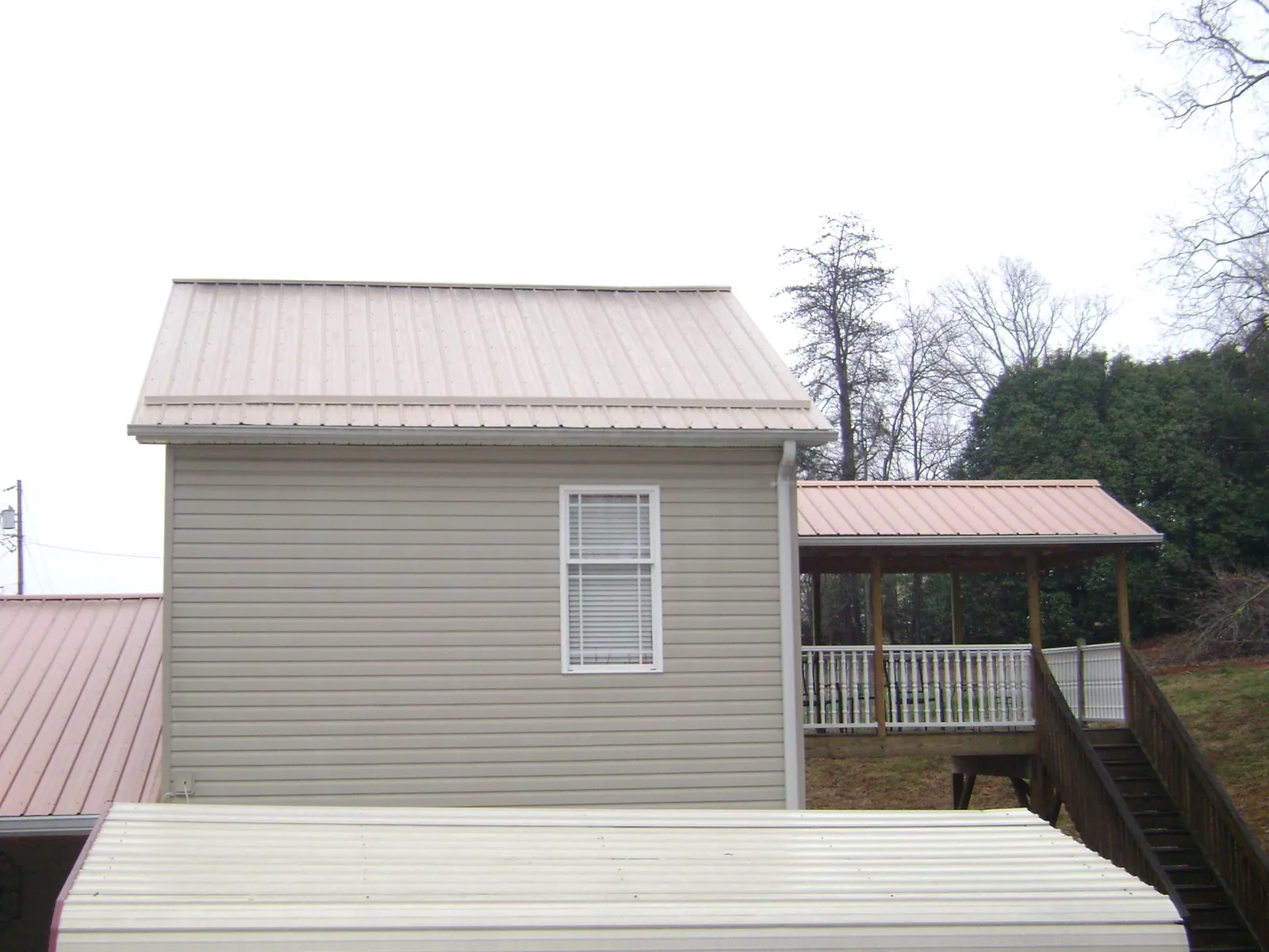 Tan metal roofs on a two story addition and attached porch, from a Roof Replacement job in Aquasco