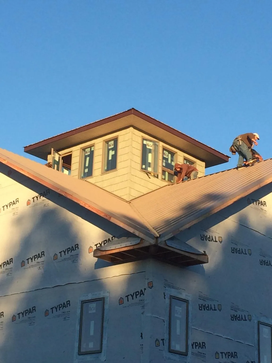 Roofers working around a rooftop cupola on a new metal roof at sunset — Roof Waterproofing in Aquasco by Roofing Brothers